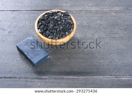 block of natural carbon soap and a pile of coal on black wood table background