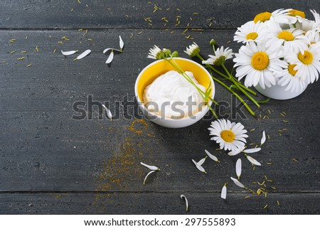 cosmetic cream and white flowers on black wooden table background