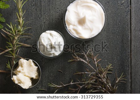 moisturizers and raw shea butter on dark wooden table