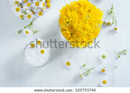 cosmetic product samples with herbal flowers on white wooden table