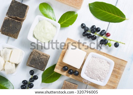 cosmetic clay, soaps, henna blocks, sponge and moisturizer on white wood table