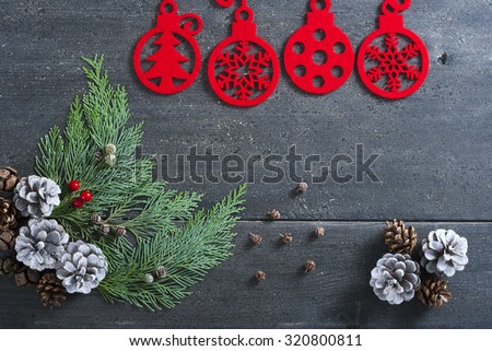 Christmas decoration background: red felt ornaments, pine and cypress cones with twigs on black wood table