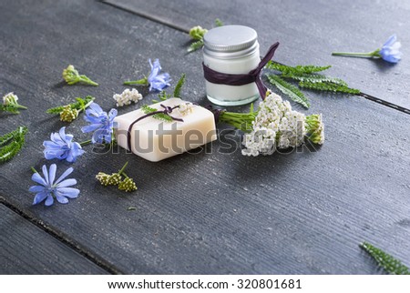 soap, cream and bath salt with chicory and yarrow herbs on black wood table