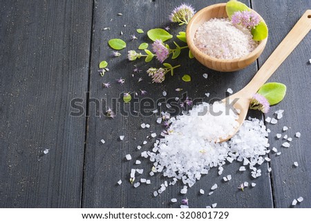bath salt at bamboo bowl and pink herbal flowers on dark wood