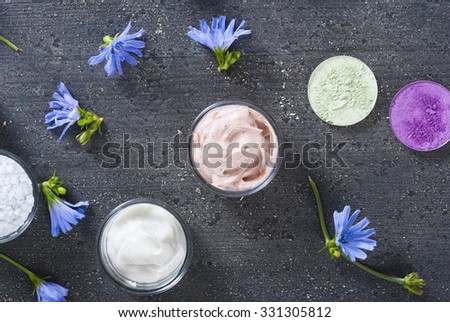 moisturizer, bath salt and face powder samples on dark wooden background