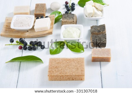 cosmetic clay, soaps, henna blocks, sponge and moisturizer on white wood table