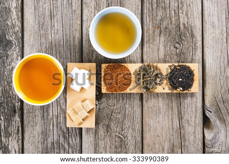 two cups of japanese tea, sugar nubs and crops on bamboo serving tray on old rusty wooden table