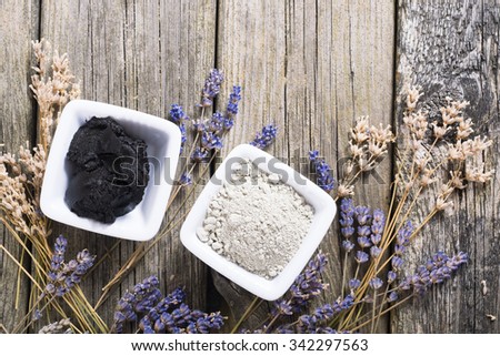 cosmetic clay powder and mud with dried lavender flowers on old weathered wooden table background