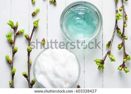 white moisturizer and blue cosmetic gel samples on white wood table