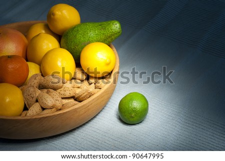 Citrus fruits, avocado and almonds in wooden bowl