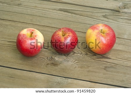 three apple on wooden table