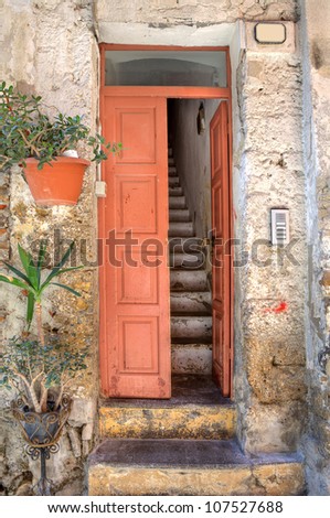Vertical oriented image of wooden door and old narrow stairs in small house at town of Ventimiglia in Liguria, Italy.
