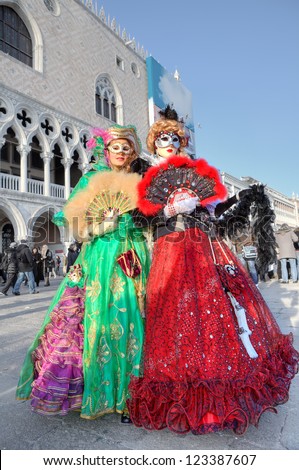 VENICE - MARCH 04: Two participants wear colorful dresses, masks and hats on St. Mark\'s square during famous traditional Venetian carnival taking place every year in Venice, Italy on March 04, 2011.