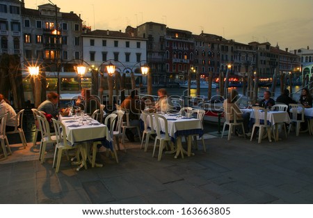 VENICE - APRIL 14: People in restaurant at evening. Outdoor restaurants located along Grand Canal close to famous Rialto Bridge are very popular with tourists visiting Venice, Italy on April 14, 2005.