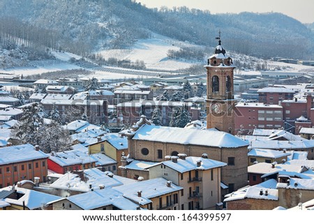 Roofs of the houses and bell tower of the church covered with snow in small town of Corneliano D\'Alba in Piedmont, Northern Italy.