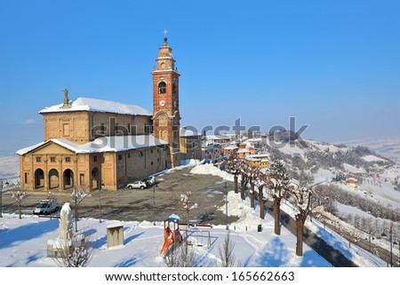 Old red brick church on small square covered with snow in town of Diano D\'Alba in Piedmont, Northern Italy.