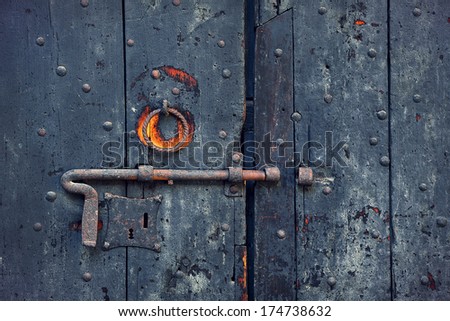Closeup image of old wooden door with metal knob and rusty bolt.