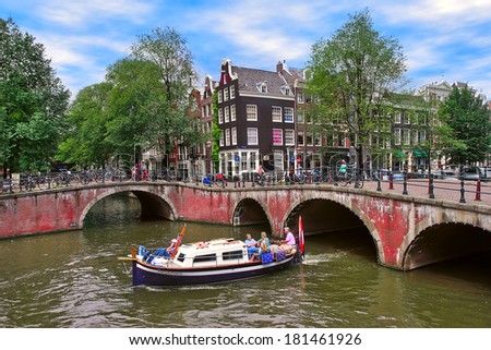 AMSTERDAM, NETHERLANDS - JULY16, 2007: Boat on canal passing by bridges and houses. Small boat trips on city canals is very popular and demanded way to explore city with tourists visiting Amsterdam.