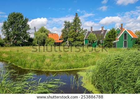 Small creek and rural wooden houses on green banks in Zaanse Schans - famous dutch village.