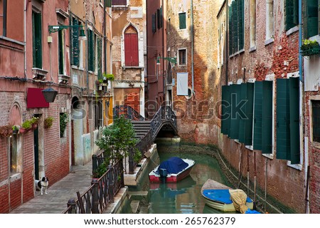 Boats on narrow canal among typical old houses in Venice, Italy.