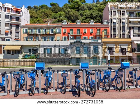 City bicycles at sharing station and colorful houses on background in Nice, France.