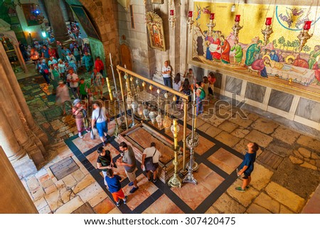 JERUSALEM. ISRAEL - JULY 16, 2015: People around Stone of Anointing and mosaic icon on the wall at the entrance to Holy Sepulcher church designate the place where Jesus\' body was prepared for burial.