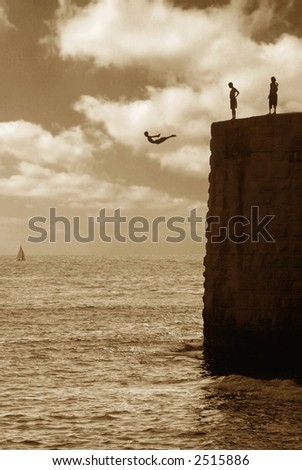 Teenagers jumping from the wall of ancient fortress in to Mediterranean Sea in Acre, Israel (sepia toned).