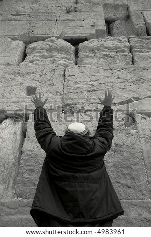 Vertical oriented photo of prayer raises hands during prayer near Western Wall (Wailing Wall) in Jerusalem, Israel.