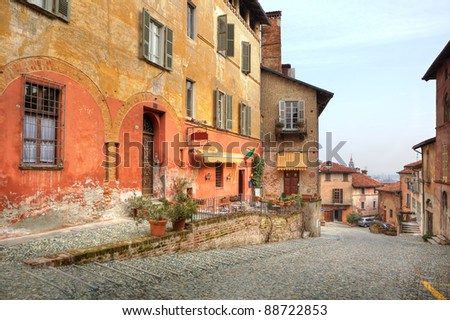 Narrow paved street among vintage multicolored houses in town of Saluzzo, Northern Italy.