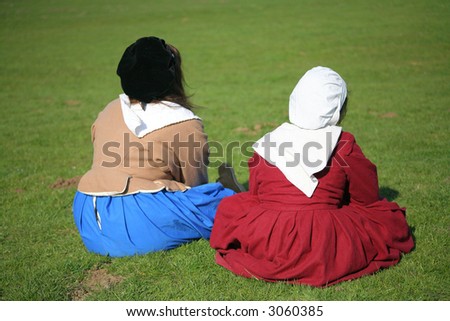 women in period costume sitting in field