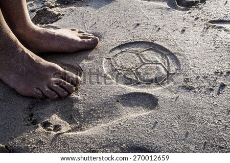 Two feet and the trace of beach soccer ball on the sand