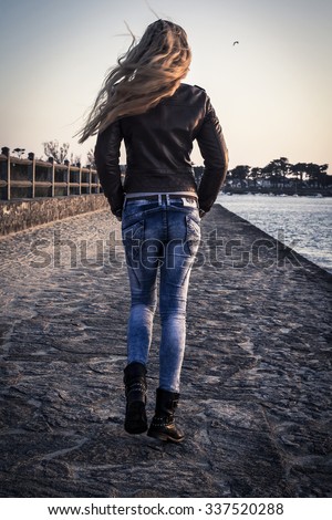 The back view of a girl walking down the village street in the wind, autumn