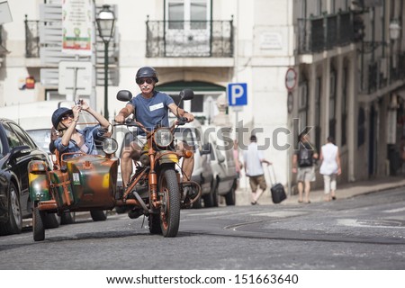 LISBON, PORTUGAL Ã¢Â?Â? AUGUST 22: a man driving the old tricar to show woman area near Se Cathedral on August 22, 2013 in Lisbon, Portugal. Unusual transport for city tours became very popular in Lisbon.