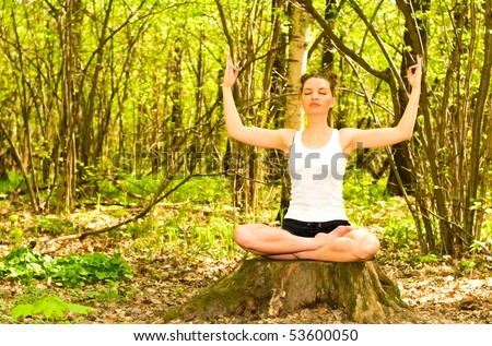 young woman in meditation pose in forest