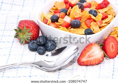 Cornflakes with fruits and a spoon on tablecloth