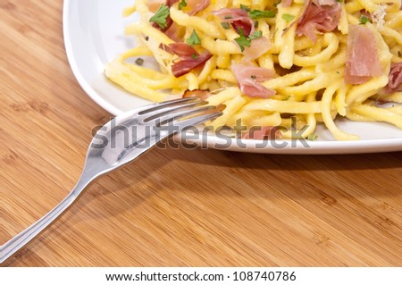 Cheese Spaetzle decorated with parsley on a plate (bamboo background)