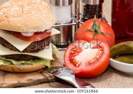 Double Burger with ingredients and cutlery on rustic background