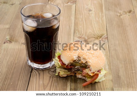 Bitten Off Burger with Softdrink on wooden background
