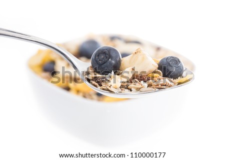 Muesli with Blueberries on a spoon and blurred bowl in the background isolated on white