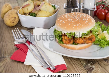 Fish Burger with fried Potatoes in a bowl on wooden background