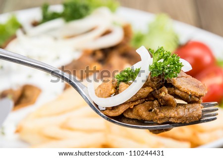 Fresh Kebab meat on a fork with portion in the background