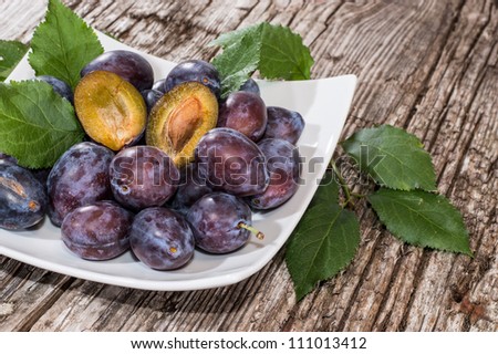 Heap of Plums in a bowl on wooden background (side view)