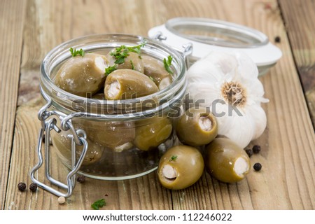 Glass filled with pickled Olives on wooden background
