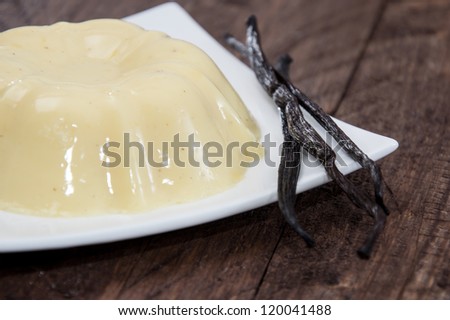 Portion of Vanilla Pudding on a plate (wooden background)