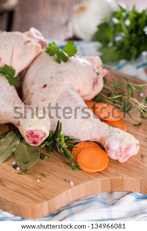 Prepared Chicken Legs with fresh herbs on a wooden board
