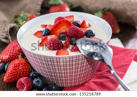 Homemade Semolina Pudding in a red bowl topped with fresh berries