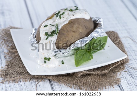 Fresh Baked Potatoe with Cream and Herbs on vintage wooden background