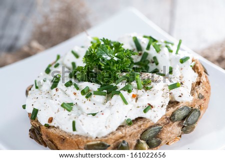 Roll with Curd and fresh Herbs on vintage wooden background
