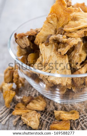 Bowl with dried Pineapple on wooden background