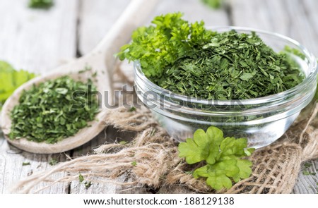 Small bowl with dried Parsley on vintage wooden background